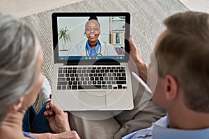 Over shoulder view of old couple patient video calling virtual doctor on laptop.