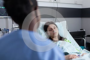 Over shoulder view of patient with nasal cannula recieving oxygen recovering on hospital bed