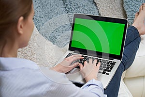 Over The Shoulder View Of Woman Lying On Sofa Using Green Screen Laptop