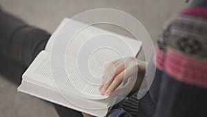 Over Shoulder View of Young african american woman is reading book sitting on floor in university library.