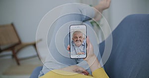 Over shoulder view of young woman daughter video calling old parent father or mature friend using conference chat online