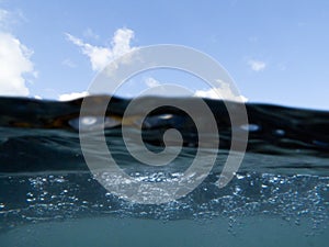 Over-under split shot of clear turbulent sea water