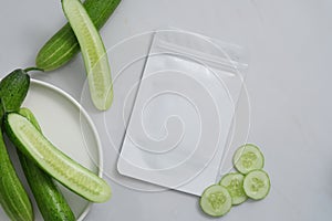 Over a white background, a dish of Cucumber and a mask sheet are decorated