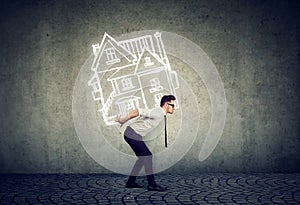 Overburdened business man carrying a house photo