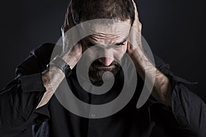 Overburdened frustrated man covering ears and looking despaired. photo