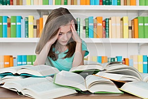 Overburdened Schoolgirl Studying In Library photo