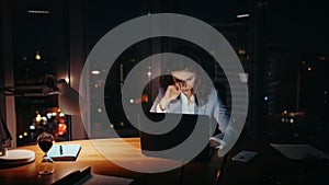 Overburdened woman working office closing tired eyes looking laptop at night.