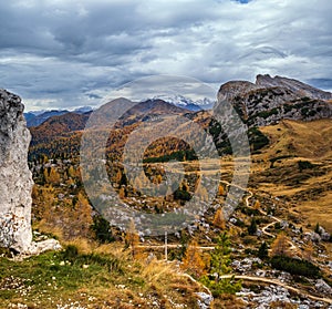 Overcast morning autumn alpine Dolomites mountain scene. Peaceful Valparola Path view, Belluno, Italy. Snowy Marmolada massif and