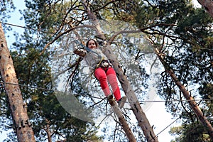 Overcoming obstacles. Little girl climbing on a rope in adventure park