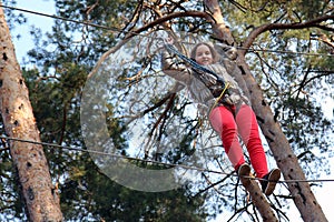 Overcoming obstacles. Little girl climbing on a rope in adventure park