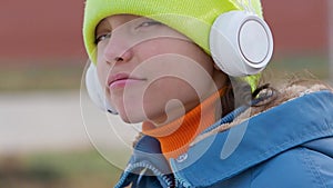 Overconfident and insolent teenager girl listening to rap music through white wireless headphones and online smartphone