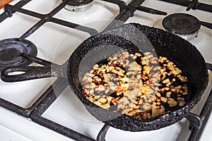 Overcooked onion in a pan. A bad kitchen. The concept of harmful food and carcinogens.