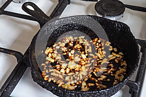 Overcooked onion in a pan. A bad kitchen. The concept of harmful food and carcinogens.