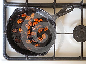 Overcooked onion in a pan. A bad kitchen. The concept of harmful food and carcinogens.