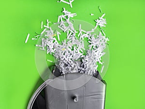 Heap of shredded paper in trash on green background