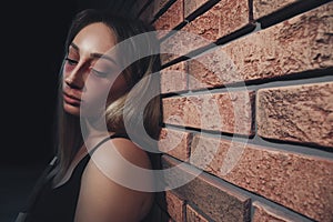Overdosed drug addicted woman near brick wall. Space for text