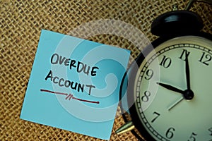 Overdue Account write on sticky notes isolated on Brown burlap laying on table