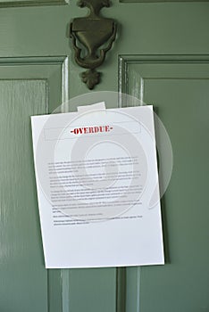 Overdue Notice Posted on a Door of a Home - Letter - Late Payment - Rent - Mortgage - Green Front Door with Knocker