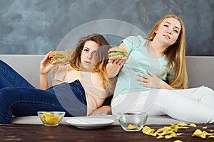 Overeaten women lying at coach eating fast food