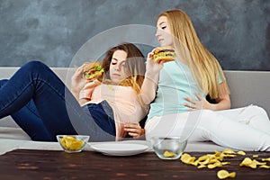 Overeaten women lying at coach eating fast food