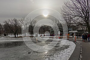Overexposed sun behind deciduous trees in winter reflecting into the ice sheet of a river