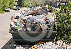 Overfilled dumpster in ghetto, trash needs recycling. Environment pollution