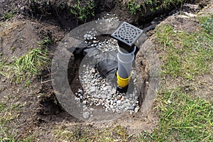 Overflow and infiltration well connected to drainage pipes, buried in a pit covered with stones.