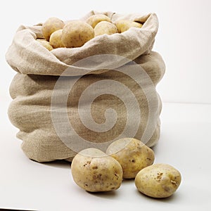 Overflowing bag of potatos on whit