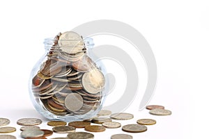 Overflowing jar of International coins on white background with copy space