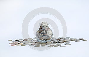 Overflowing jar of International coins on white background with copy space