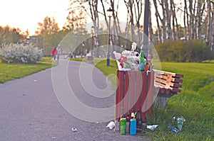 Overflowing trash can in the public park on sunset.The plastic pollution. photo