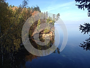 Overgrown cliff shore juts out into the depths of the lake