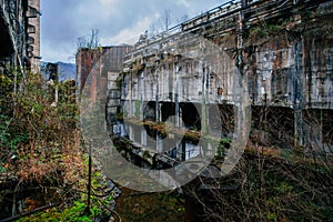 Overgrown ruins of industrial building. Abandoned, destroyed by war power plant in Tkvarcheli Tquarhcal, Abkhazia