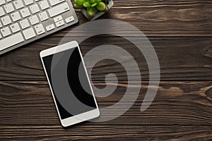 Overhead above view photo of keyboard succulent and mobile phone with copyspace on screen on dark wooden backdrop