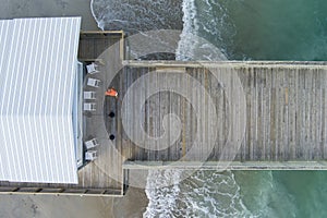 overhead aerial shot of Crystal Pier with green ocean water, people on the sandy beach and waves rolling into the shore
