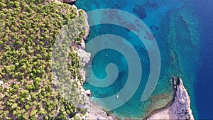 Overhead aerial shot from drone of Mylokopi bay and beaches, Greece, with beautiful glimmering and shining sea with tones of blue