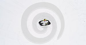 Overhead aerial top view over father mother and children doing ring around rosie on white covered winter snowy field