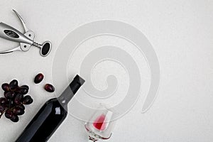 Overhead angled view of a large bottle of red wine, drinking glass on white background