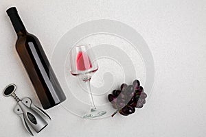 Overhead angled view of a large bottle of red wine, drinking glass on white background