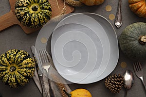 Overhead autumn thanksgiving dinner place setting with pumpkins cutlery and an empty plate