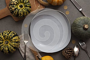 Overhead autumn thanksgiving dinner place setting with pumpkins cutlery and an empty plate