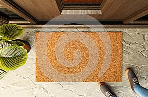 Overhead of blank doormat and shoes of a man standing on the porch at the front door