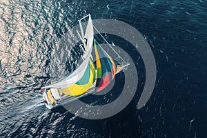 overhead capture of a yacht with colorful sails unfurled on the open sea