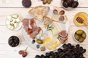 Overhead of cheese plate with pieces moldy cheese, prosciutto, p