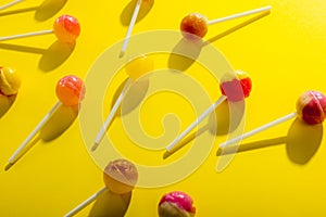 Overhead close-up view of scattered lollipops against yellow background photo