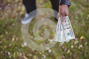 Overhead closeup shot of a male holding twenty dollar bills wit ha blurred background