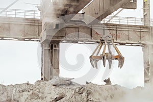 Overhead crane with mechanical multivalve clamshell grab in hot outdoors industrial plant shop