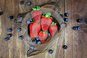 Overhead Display of Fresh Strawberries and Blueberries in a Rustic Wood Bowl