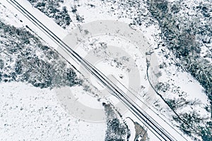 overhead drone aerial view of a road in a snowy landscape, winter time transportation concept