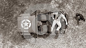 Overhead, drone, looking down on Male army officer in uniform resting on back of military vehicle